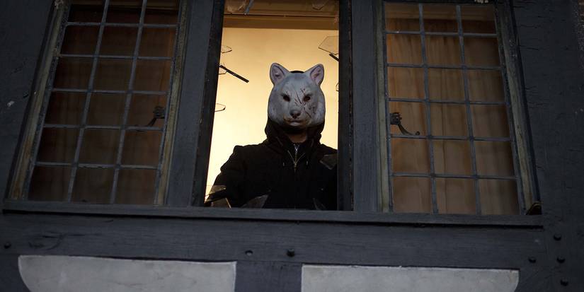 Um homem com máscara de urso olhando pela janela em You're Next (2011)