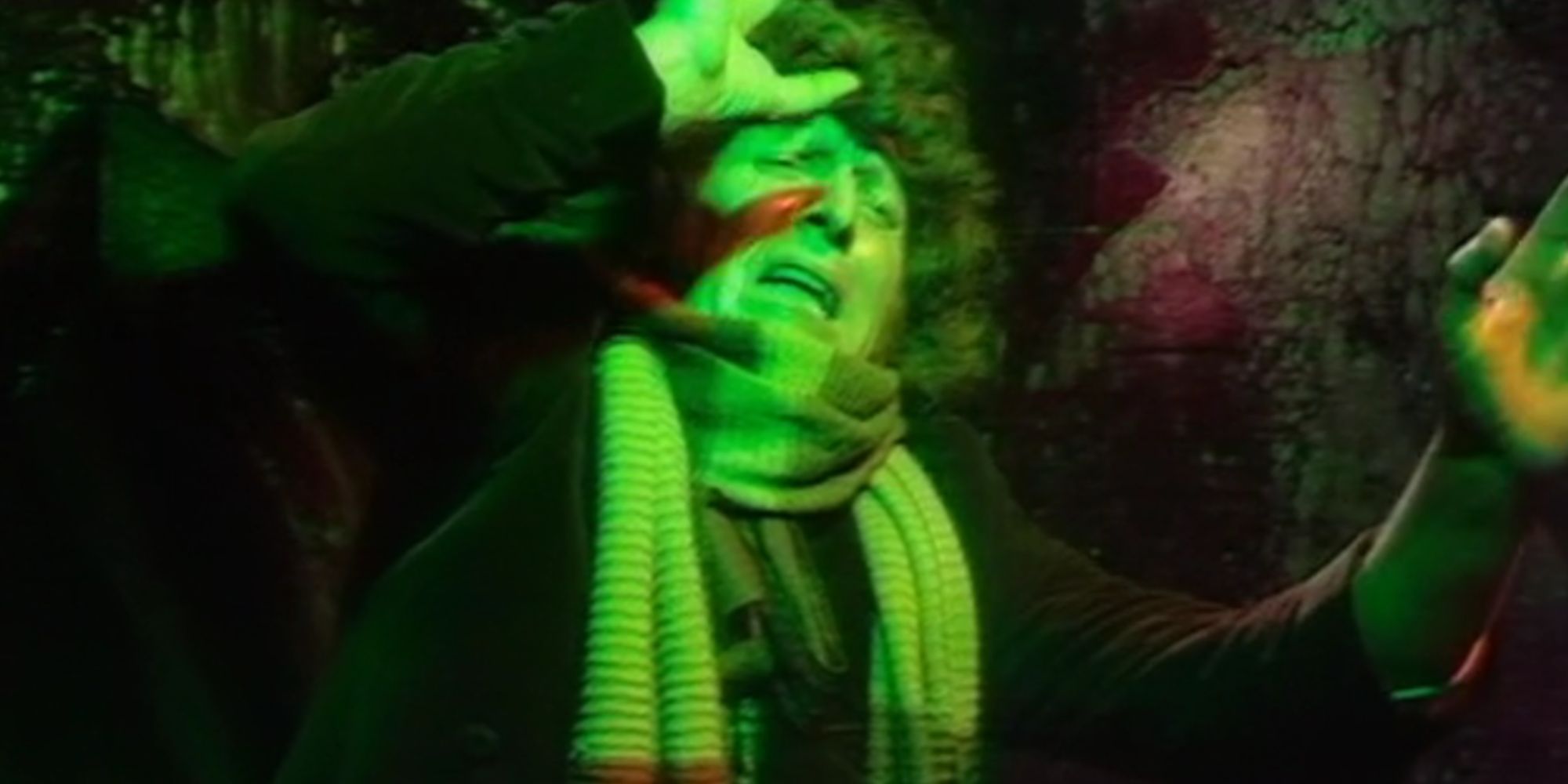 Tom Baker bathed in green light looking afraid as the Fourth Doctor in Doctor Who