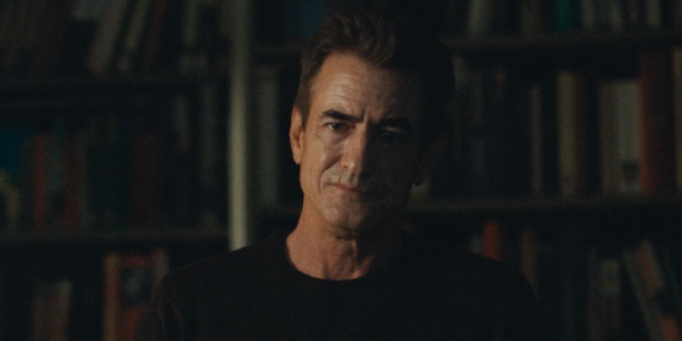 Blackwater Lane Dermot Mulroney against library stack of books, looking concerned 