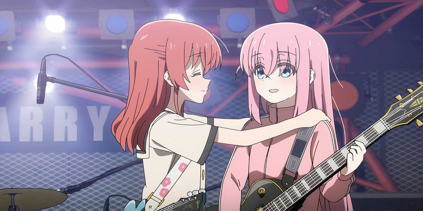 Kita puts her hands and smiles at Bocchi who is holding her guitar and also smiling.