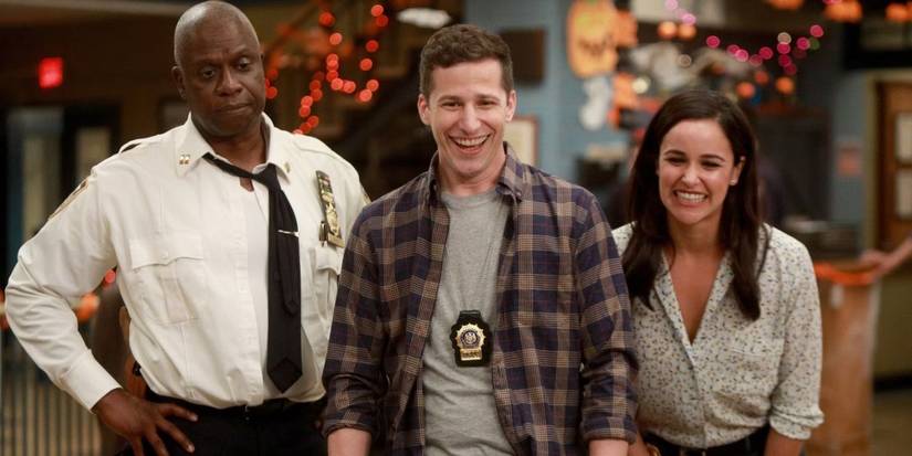 Holt com as mãos na cintura e Peralta e Santiago sorrindo no Brooklyn Nine-Nine
