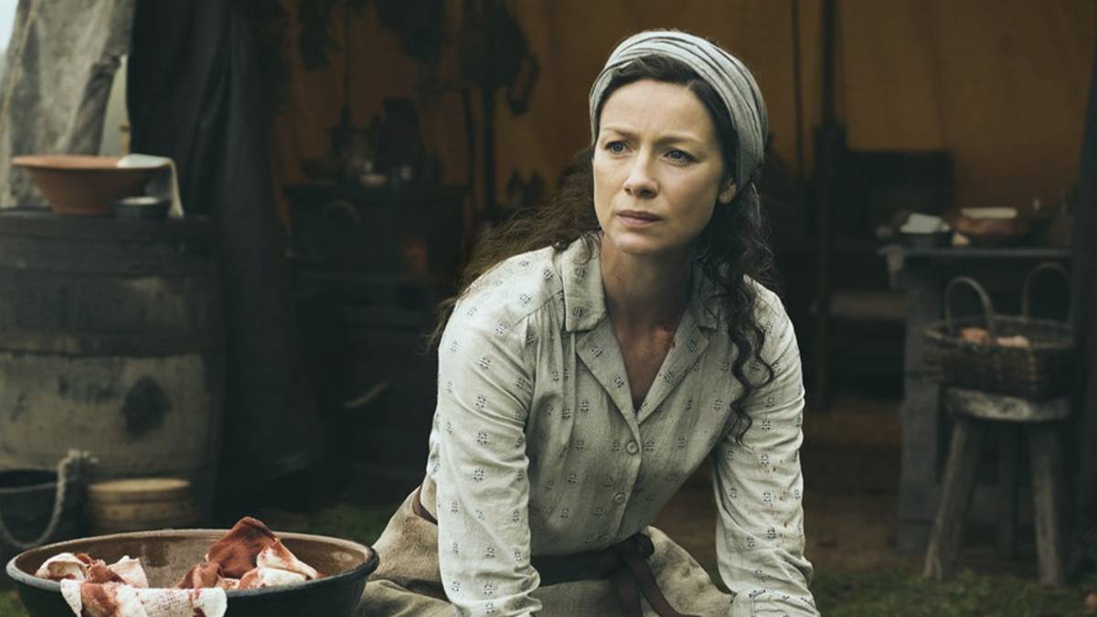 Claire outside cleaning blood from her tent in Outlander