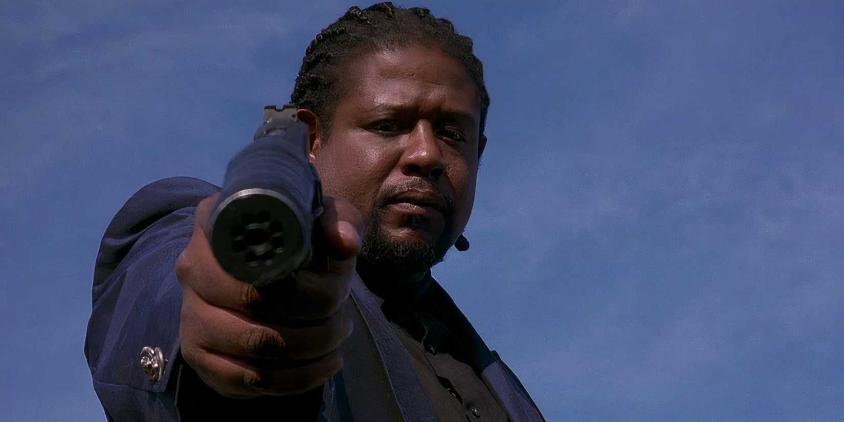 From an angle looking up at Forest Whitaker, he points a gun to the camera.