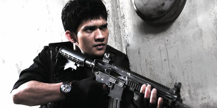 Iko Uwais holding a machine gun in The Raid: Redemption