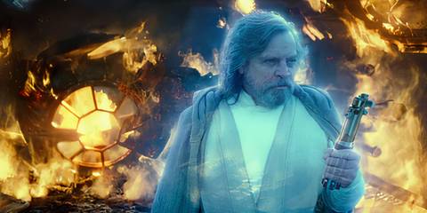 Luke Skywalker's (Mark Hamill) Force ghost holds a lightsaber in front of a burning ship in the Rise of Skywalker