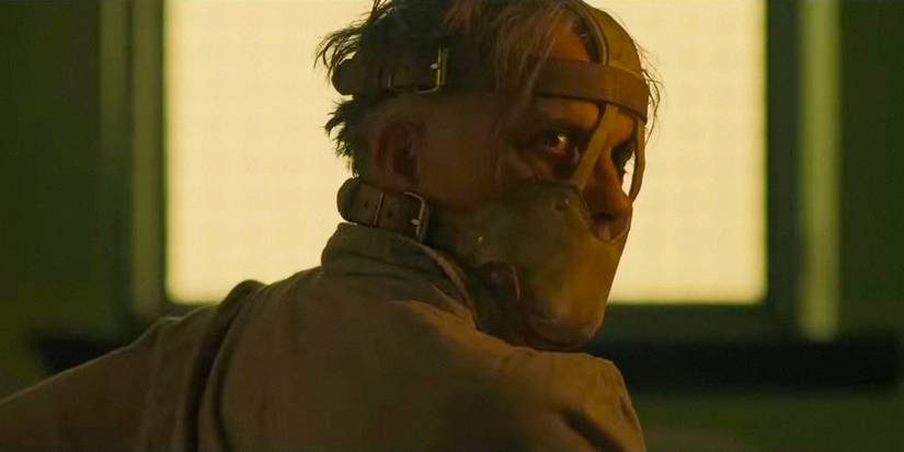 A person with an insane expression wearing a muzzle in Oddity