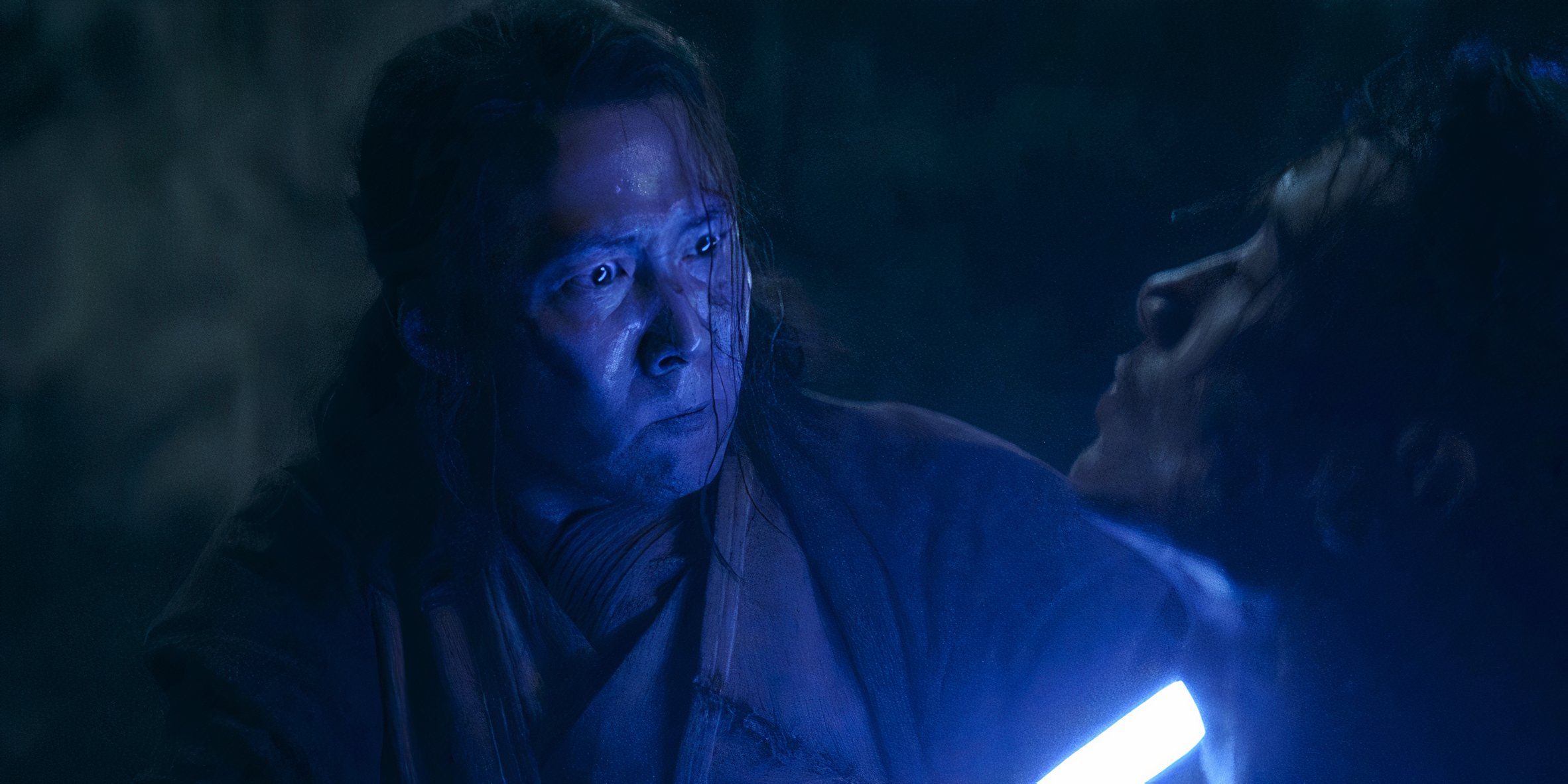 Master Sol (Lee Jung-jae) with a furious look on his face as he holds his blue lightsaber to Qimir's (Manny Jacinto) neck in The Acolyte