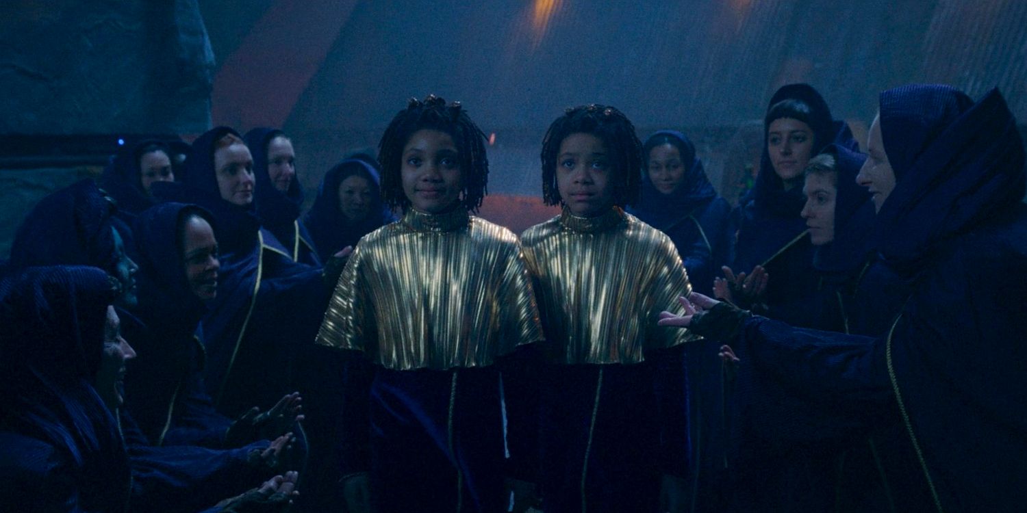 Little Osha (Lauren Brady) and Little Mae (Leah Brady) standing side-by-side in their Ceremony outfits in The Acolyte season 1 episode 3