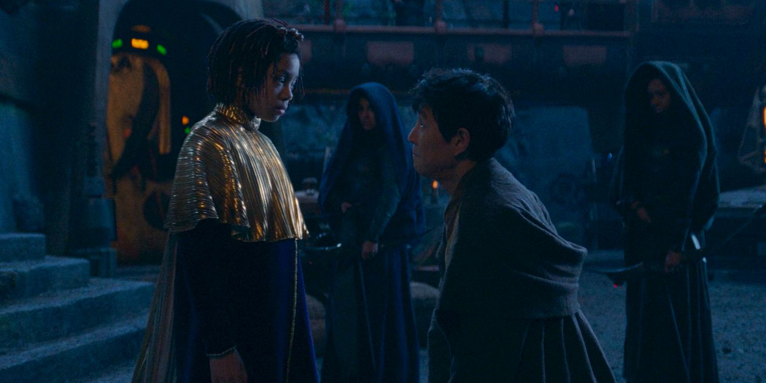 Little Osha (Lauren Brady) looking down at a younger Master Sol (Lee Jung-jae) who is kneeling in front of her in The Acolyte season 1 episode 3 