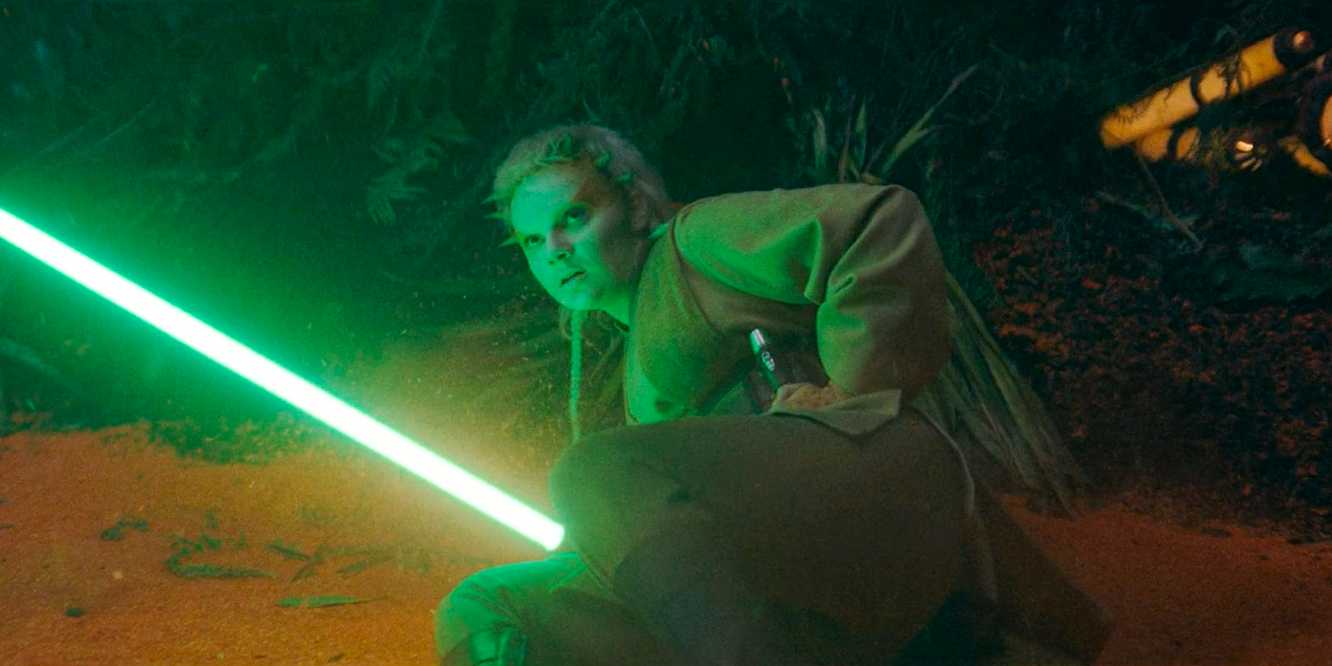 Jecki Lon (Dafne Keen) holding her lightsaber while lying on the ground in The Acolyte season 1 episode 5