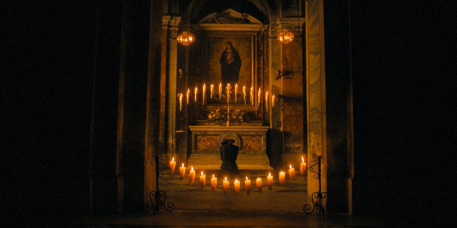 Margaret praying in the church surrounded by candles in The First Omen