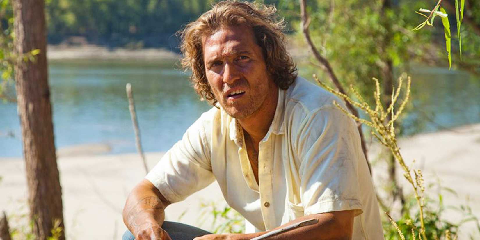 Matthew McConaughey em Mud sentado à beira da água