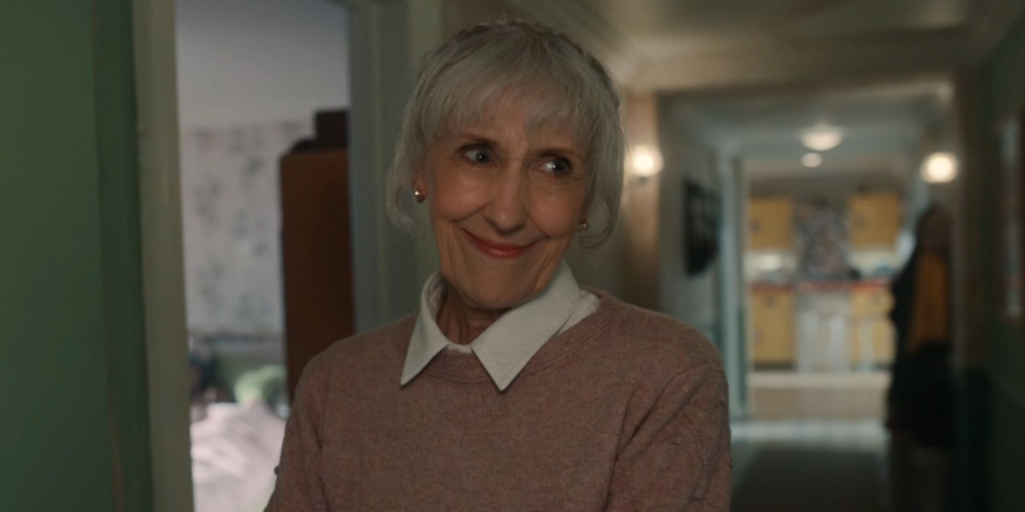 Anita Dobson as Mrs. Flood standing in the Sundays' home and smiling in Doctor Who.