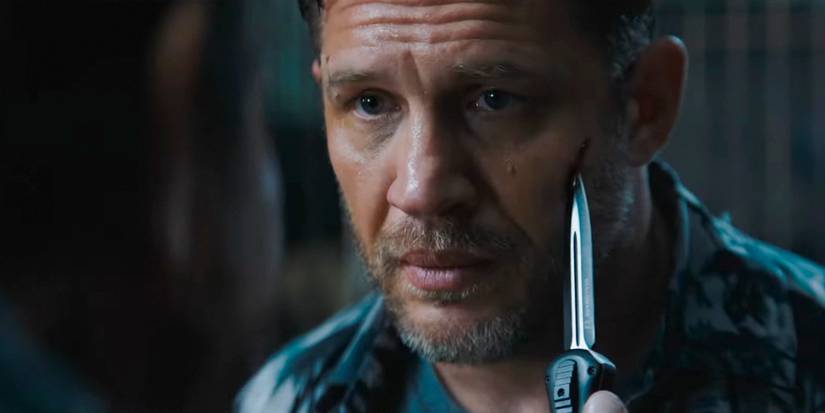 Someone holds a knife to Eddie's (Tom Hardy) cheek in Venom: The Last Dance