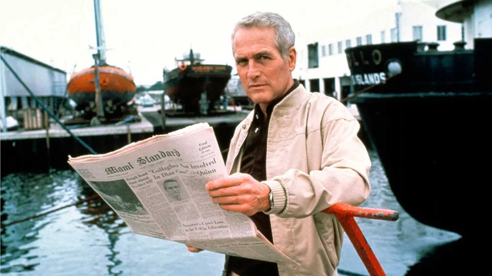 Paul Newman lê um jornal enquanto está em um cais em Absence of Malice