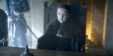 Bella Ramsey as Lyanna Mormont sitting in a chair in Game of Thrones