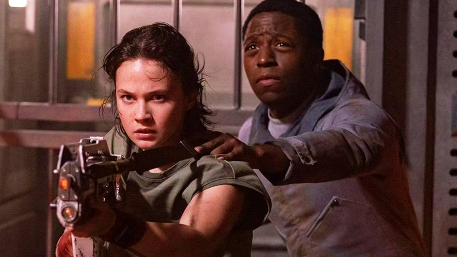 Cailee Spaeny holds a gun and David Jonsson holds onto her in Alien Romulus