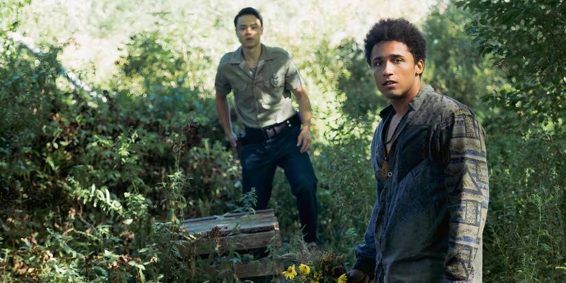 Ellis looks over his shoulder while standing in the woods in From