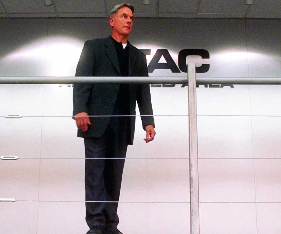 Gibbs standing alone in front of the MTAC sign in NCIS