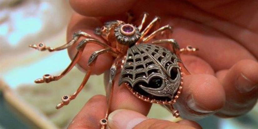 Hands carefully holding the Faberge spider brooch on Pawn Stars.-1