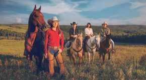 Amy stands by her horse while Tim, Lou, and Jack sit on their horses in the background in Heartland