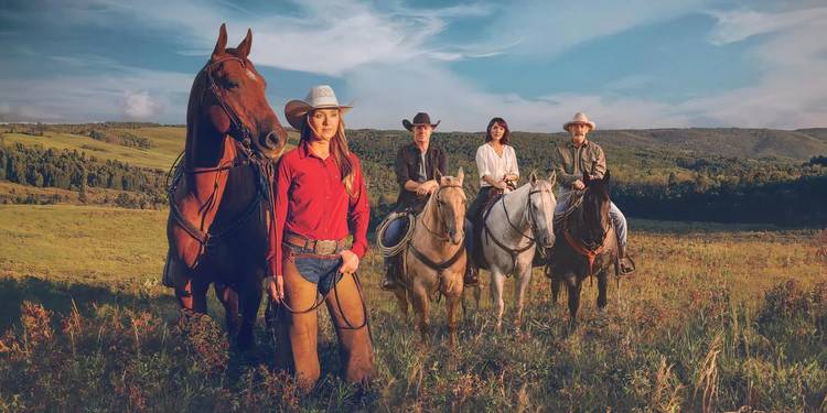 Amy stands by her horse while Tim, Lou, and Jack sit on their horses in the background in Heartland