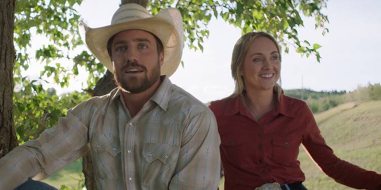 Nathan and Amy sit under a tree together in Heartland