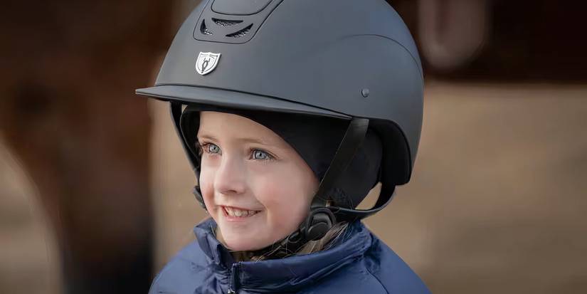 Lyndy smiles and looks up while wearing a horse helmet in Heartland