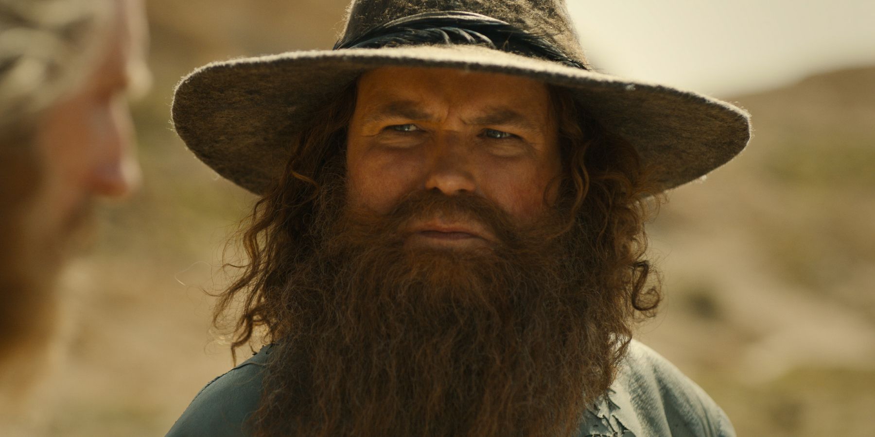 Rory Kinnear as Tom Bombadil looking to the side with concern in The Lord of the Rings: The Rings of Power season 2.