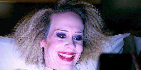 Sarah Paulson's Sally looks at a phone laughing in American Horror Story Hotel