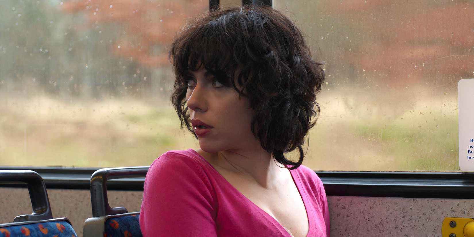 Лара (Скарлетт Йоханссон) сидит в автобусе, оглядываясь назад в фильме "Под кожей"