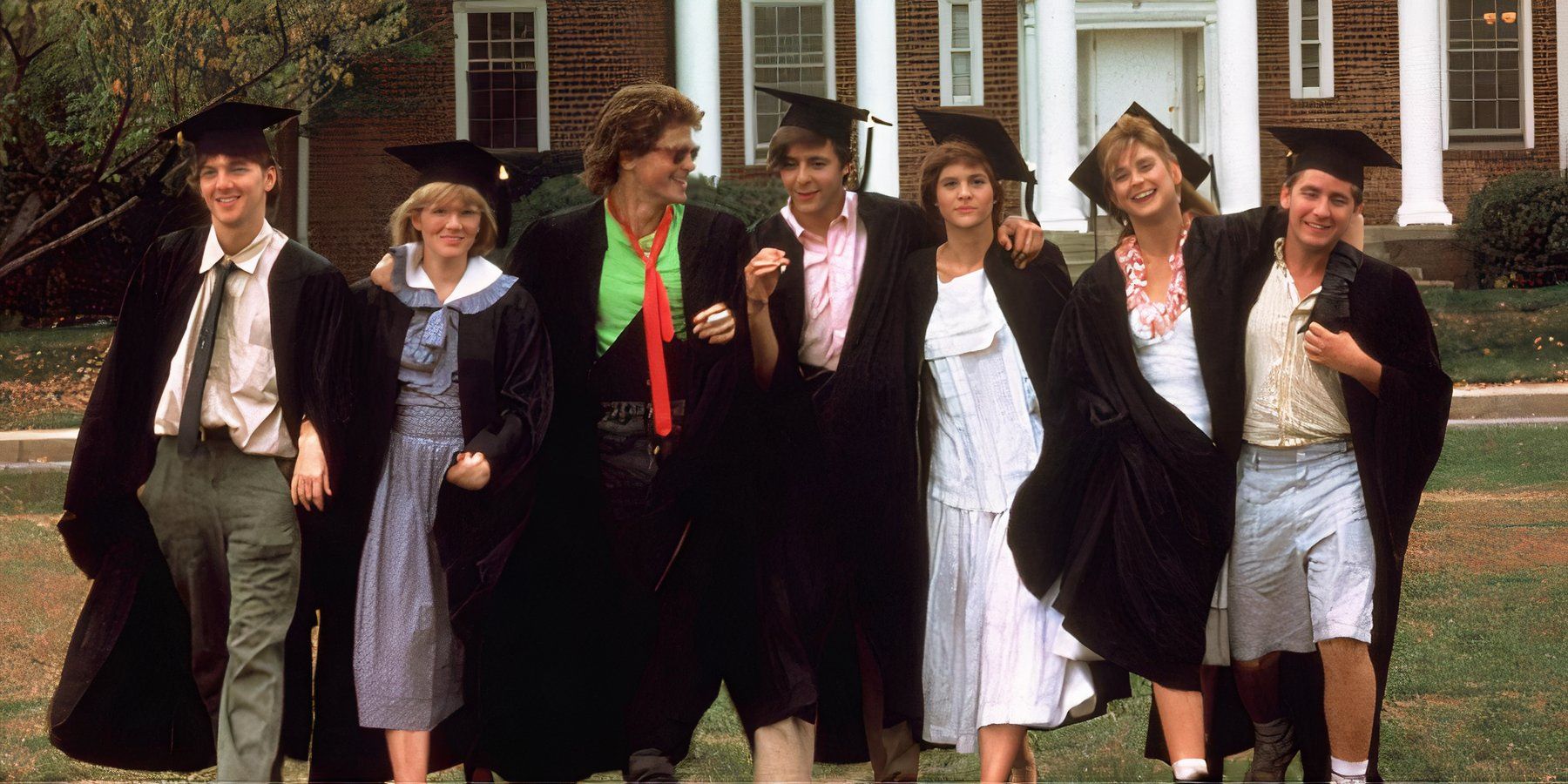Captura de tela dos sete personagens principais do filme St Elmo's Fire saindo de um prédio universitário usando bonés e vestidos de formatura.