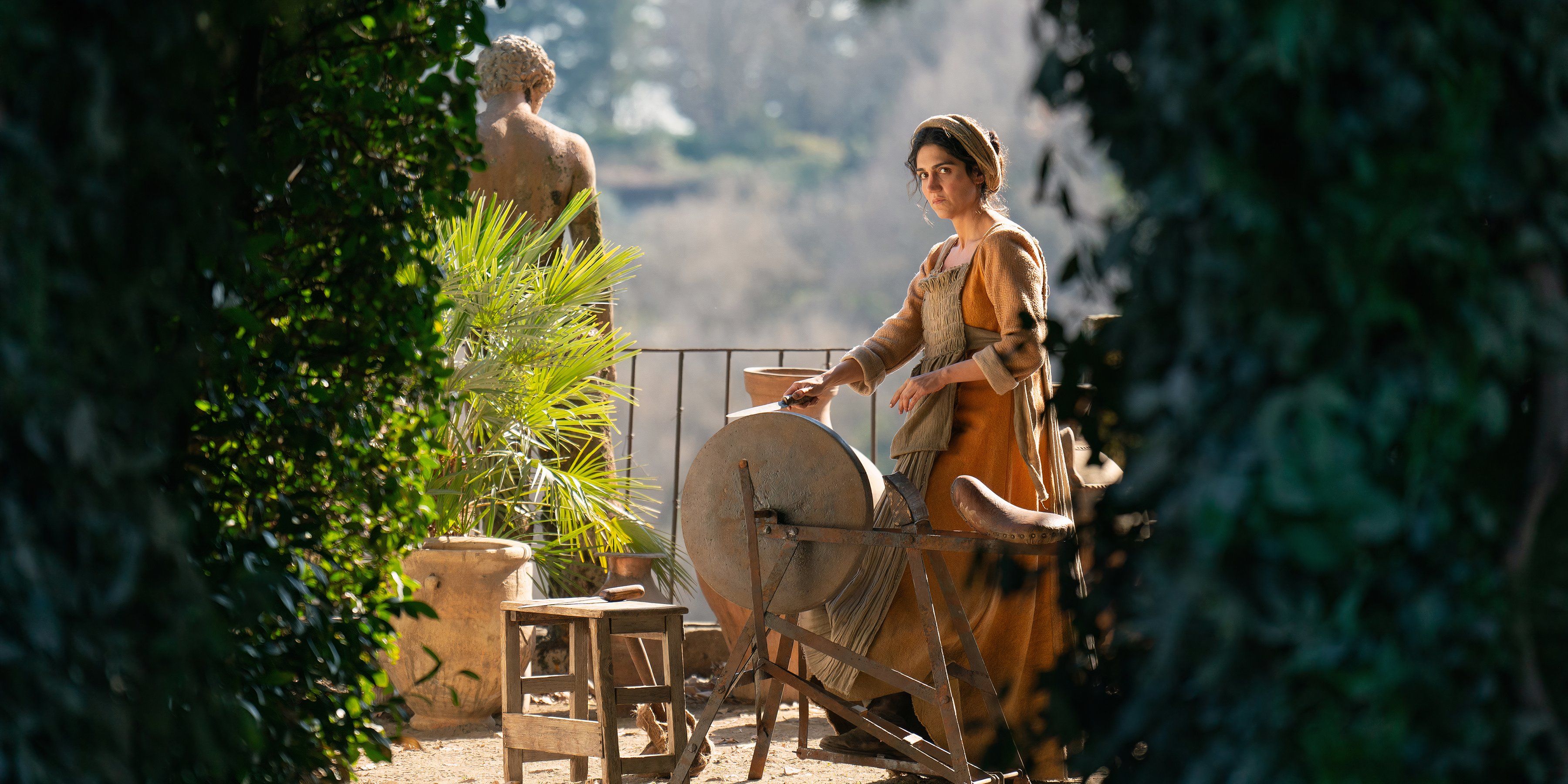 Stratilia is at the spinning wheel in the garden in The Decameron season 1, episode 1-1