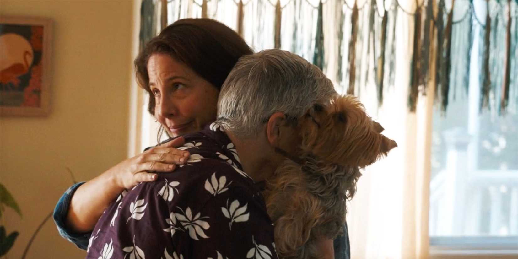 Teddi hugging a dog-holding Velma while joyfully rolling her eyes