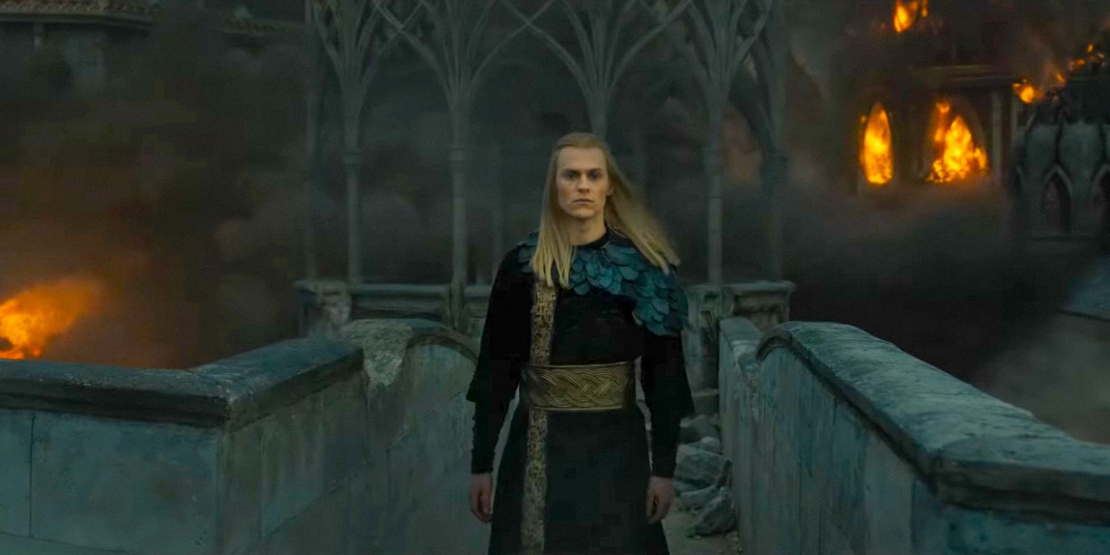 Halbrand (Charlie Vickers) with a palace in flames behind him in The Lord of the Rings:The Rings of Power Season 2