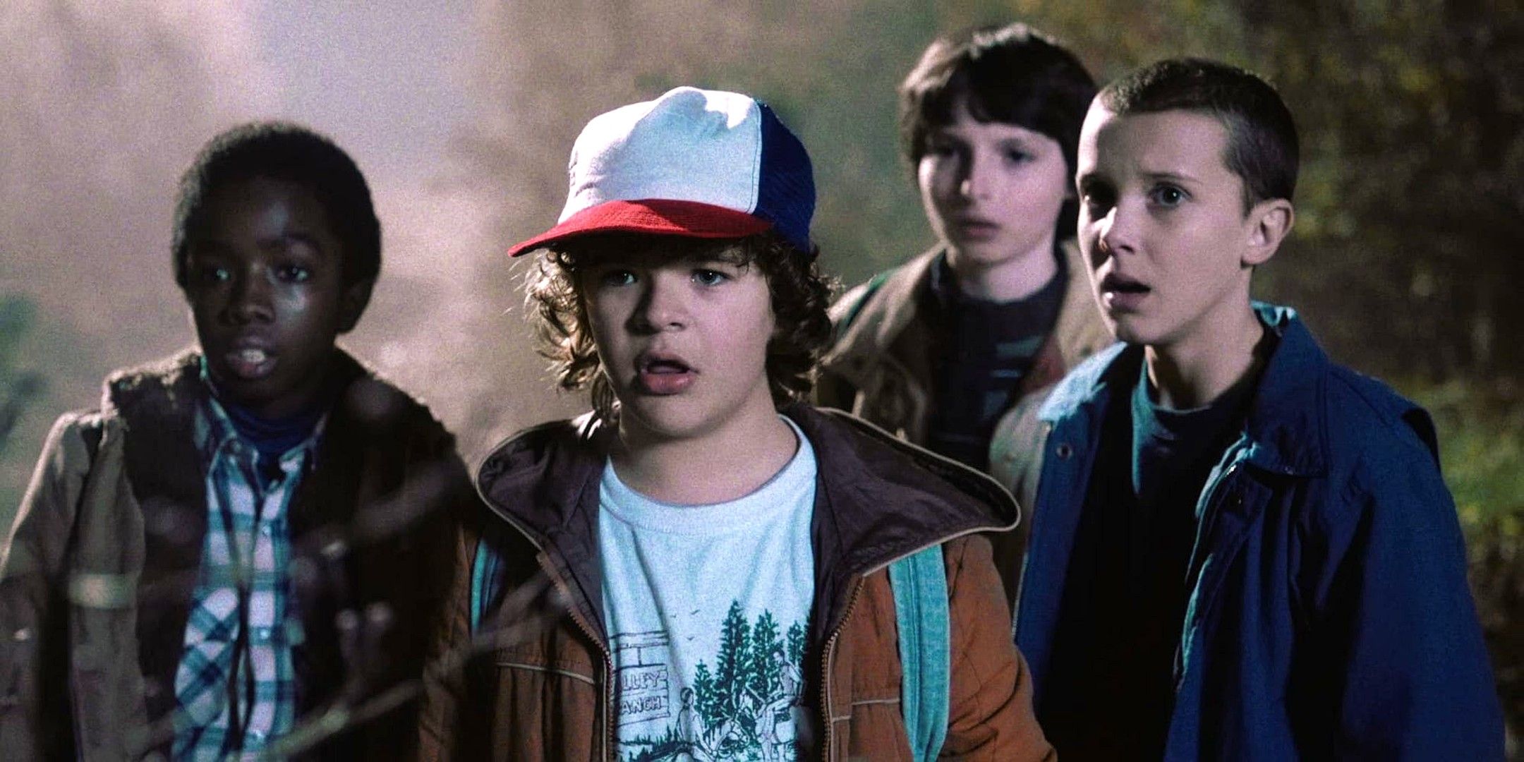 Lucas, Dustin, Mike, and Eleven standing together and looking worried in Stranger Things