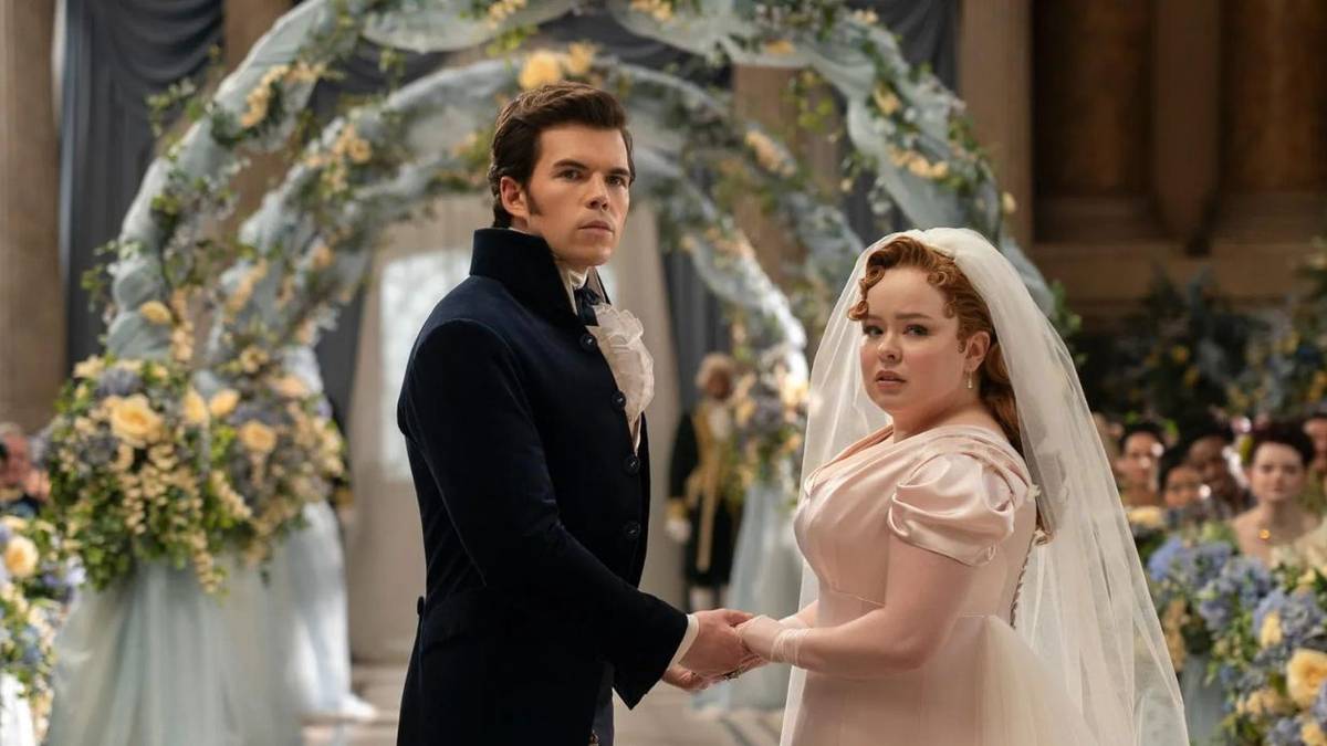 Colin Bridgerton and Penelope Featherington on their wedding day, they are looking at something off camera.