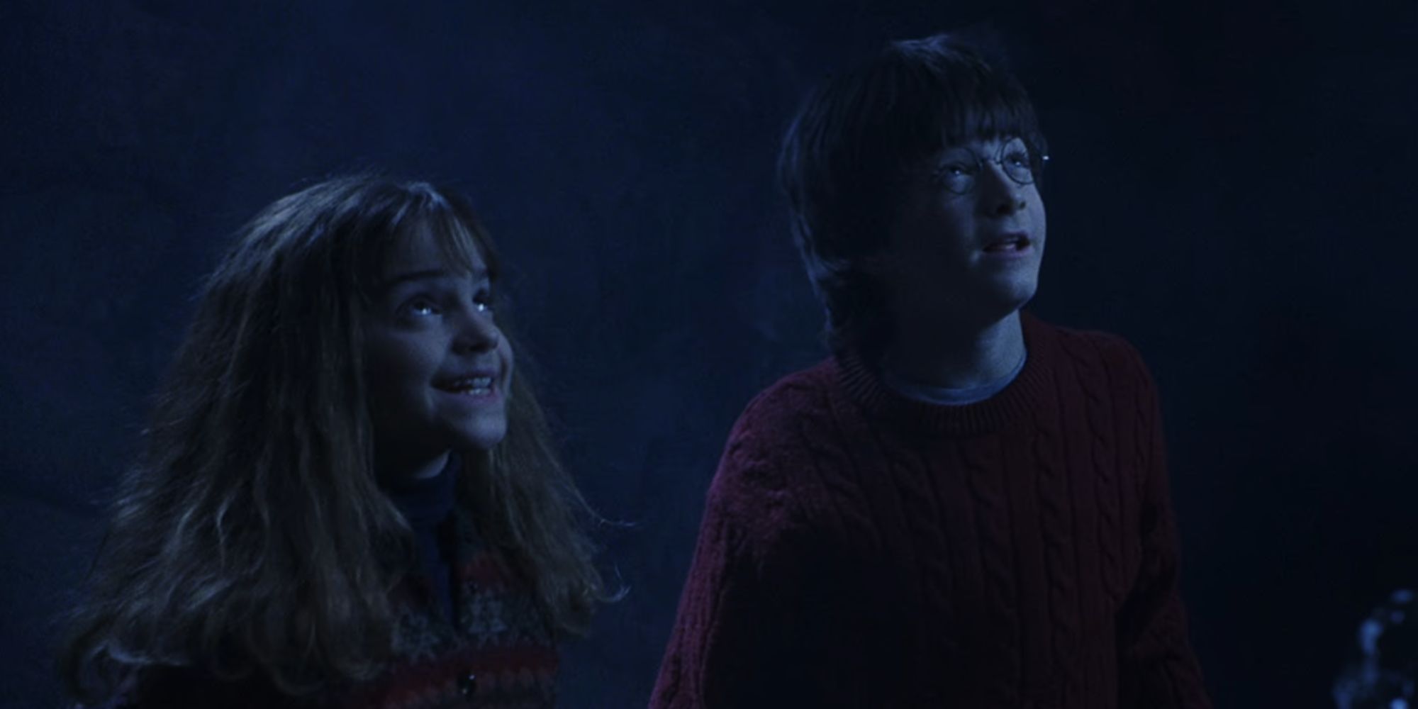 Daniel Radcliffe as Harry Potter and Emma Watson as Hermione Grander looking up in The Sorcerer's Stone