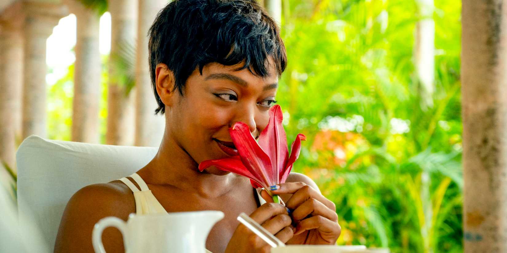 Frida (Naomi Ackie) smiling while smelling a flower in Blink Twice (2024)