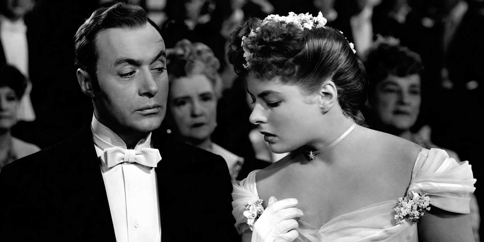 Ingrid Bergman looks down at the watch in Charles Boyer's hands. 