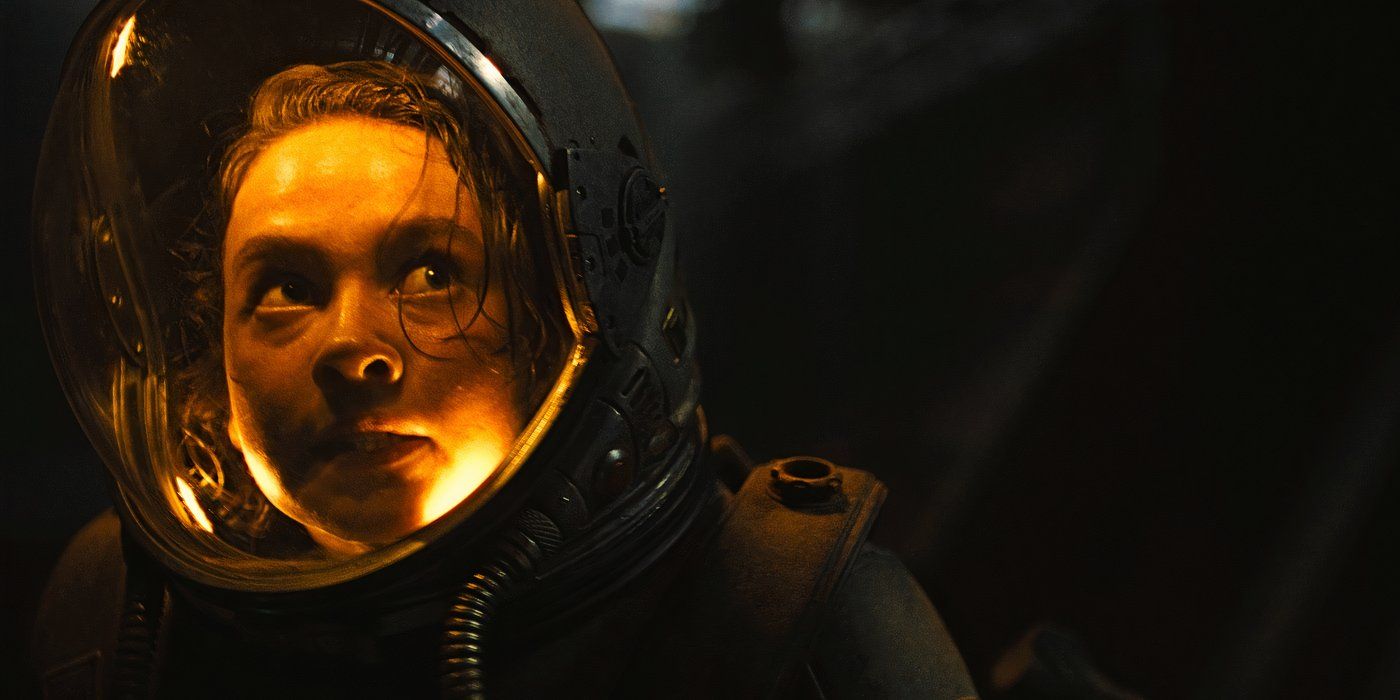 Close up of Cailee Spaeney as Rain in a space helmet lit by yellow light in Alien Romulus