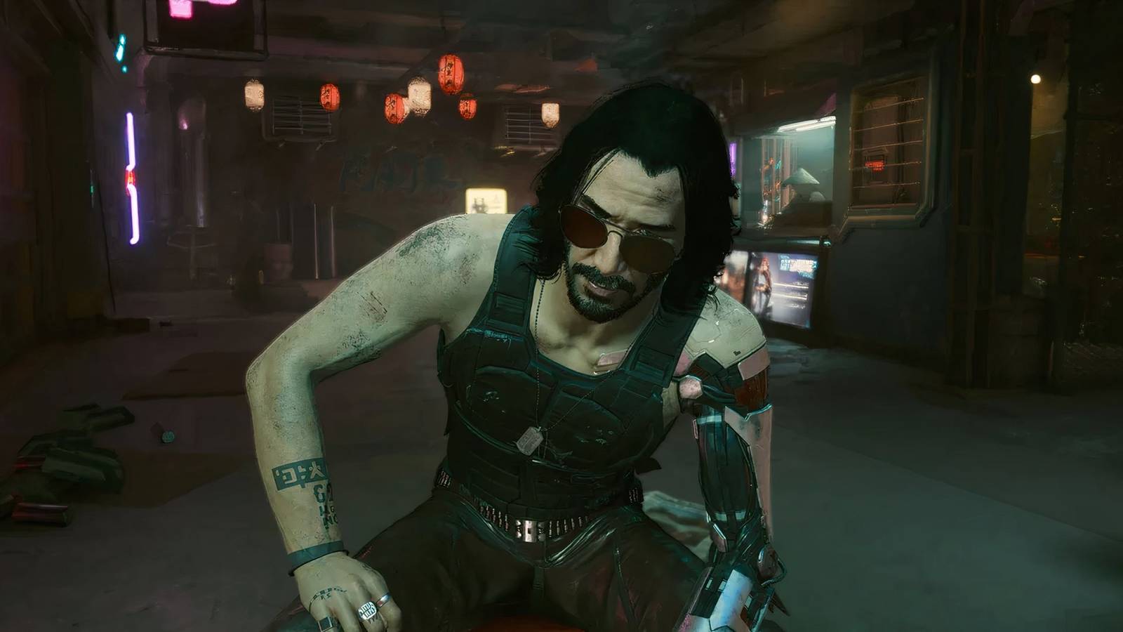 Johnny sat on a chair looking at V from behind his sunglasses in Cyberpunk 2077.