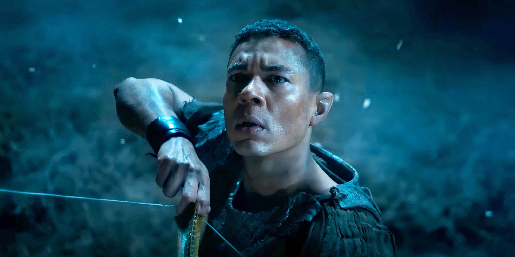 Ismael Cruz Córdova as Arondir pulling back a bowstring in The Lord of the Rings The Rings of Power season 2