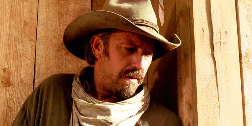 Kevin Costner as Charlie leaning on a door in Open Range