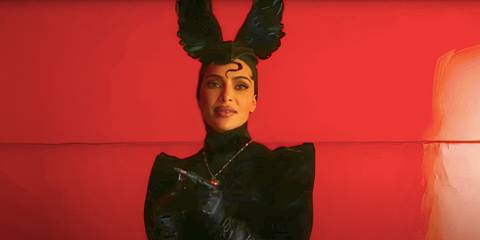 Kim Kardashian's Siobhan stands in a red room dressed as a witch in American Horror Story Delicate