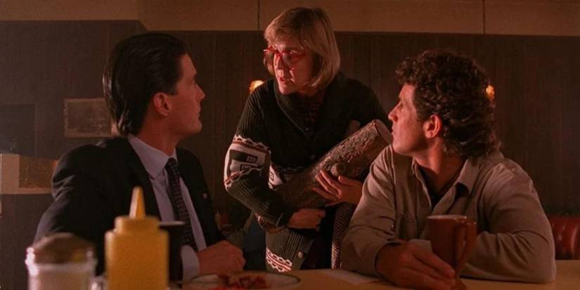 The Log Lady in Twin Peaks. In the still, she's at the diner with Cooper and Truman, explaining something to Dale.