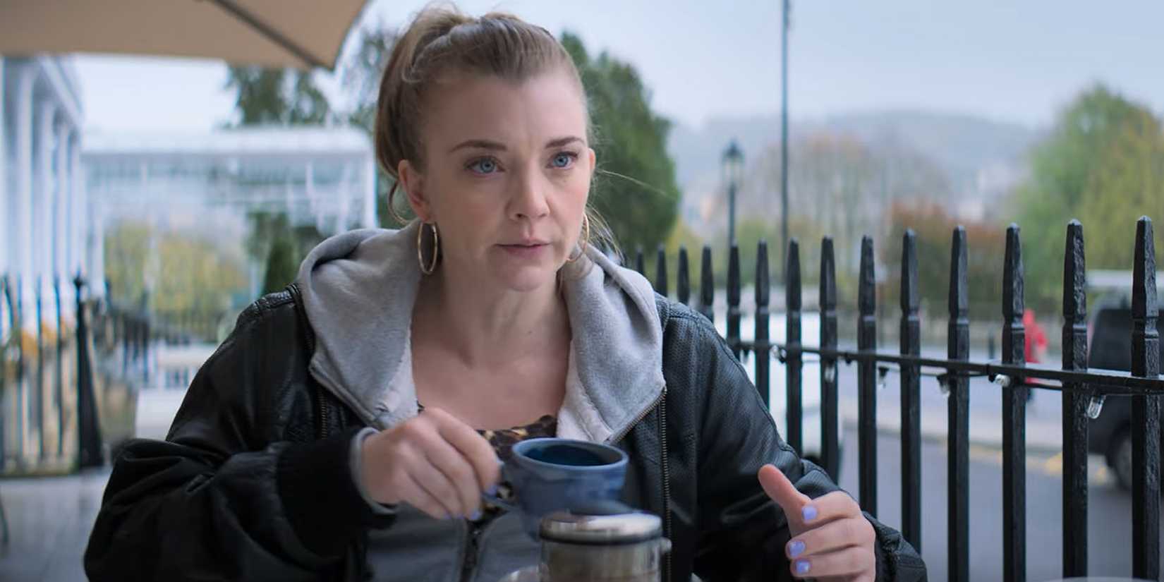 Natalie Dormer sitting at a table outside in The Wasp