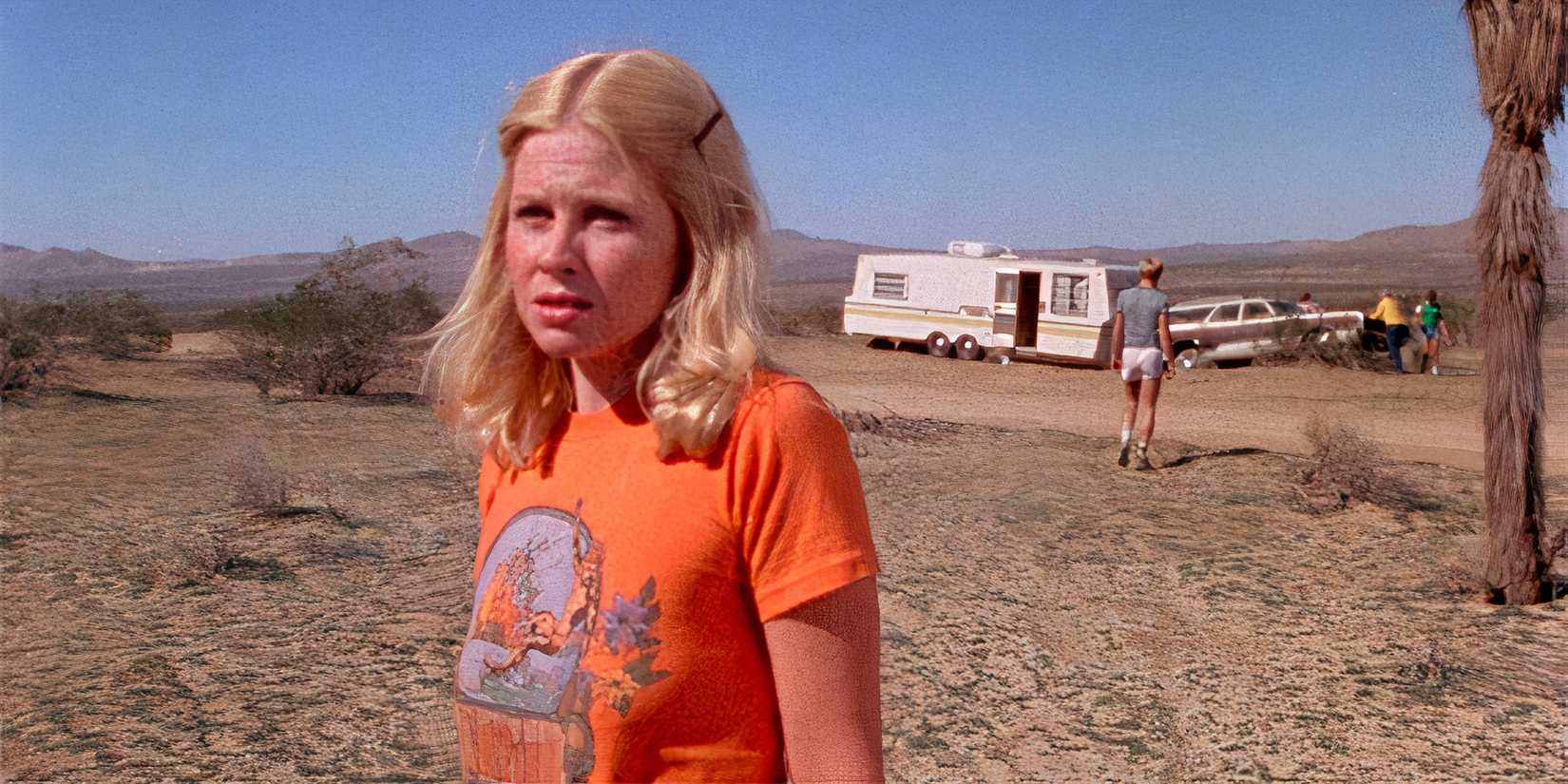 Brenda Carter Stands outside in a mountain or desert landscape, looking off camera 