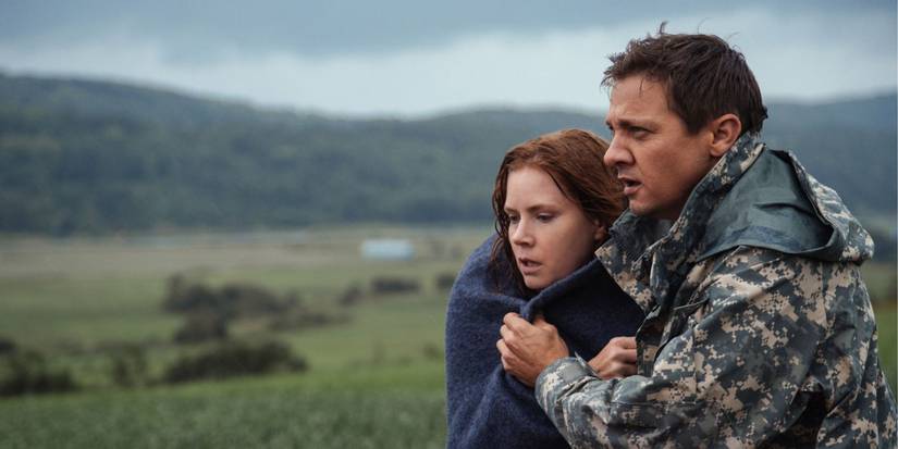 Jeremy Renner as Ian Donnelly holding Amy Adams as Louise Banks in Arrival.