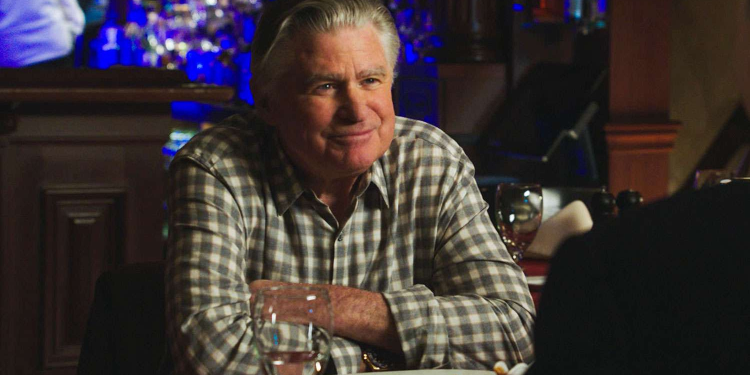 Blue Bloods Lenny sitting at a restaurant with his arms crossed and a mischievous smile